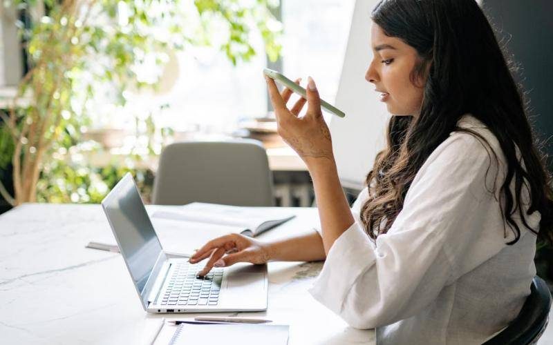Business owner working on a laptop while speaking into her phone
