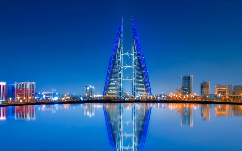 Bahrain World Trade Center towers lit up at dusk and reflected in the water, Manama